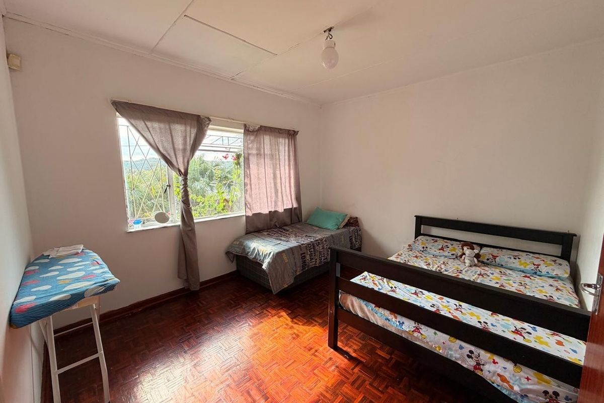 A bedroom featuring parquet flooring, security bars on the window, and a tiled ceiling. The room requires cosmetic updates to improve its overall condition.