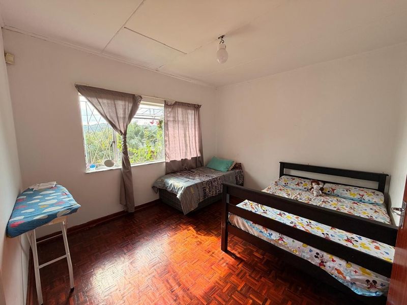 A bedroom featuring parquet flooring, security bars on the window, and a tiled ceiling. The room requires cosmetic updates to improve its overall condition.