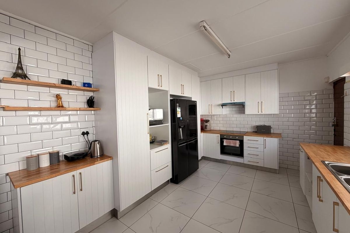 Modern kitchen featuring white cabinetry, subway tile backsplash, wooden countertops, and integrated appliances with large format floor tiles.