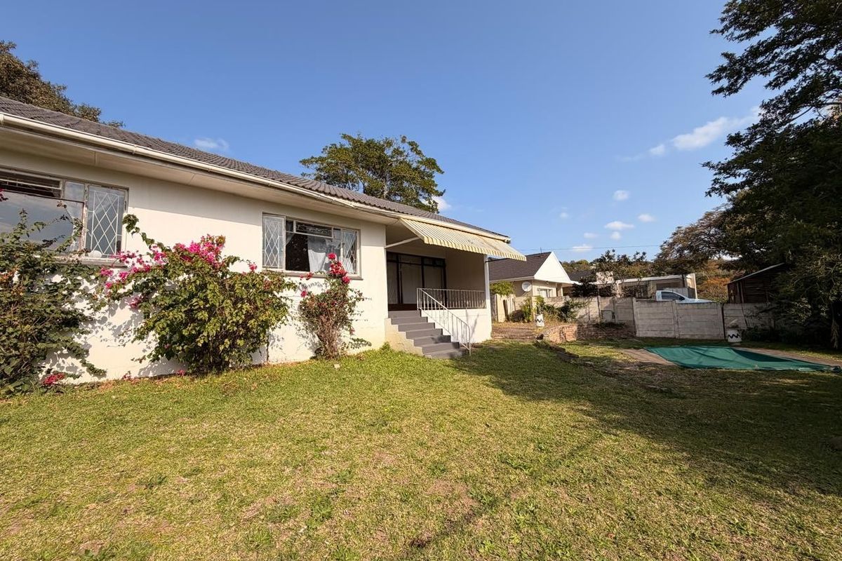 Rear view of the house featuring a lawn, a swimming pool, a covered patio area, and a precast concrete boundary wall.