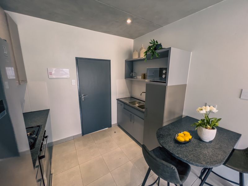 Compact modern kitchen featuring built-in cabinetry, stainless steel sink, integrated oven and hob, and tiled flooring.