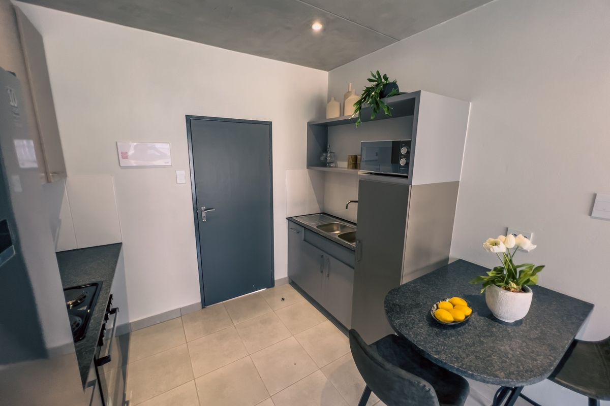 Compact modern kitchen featuring built-in cabinetry, stainless steel sink, integrated oven and hob, and tiled flooring.