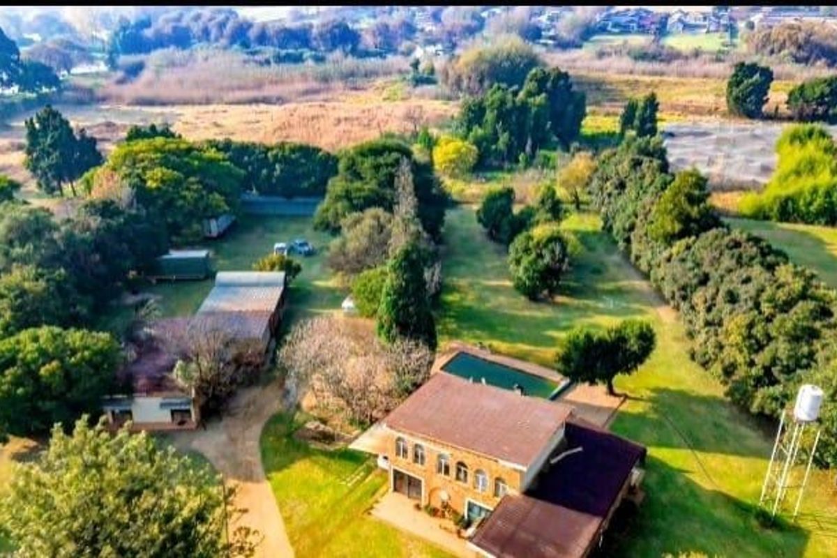 Aerial view of a large industrial property featuring a main building, swimming pool, water tank, and extensive surrounding grounds with mature trees.