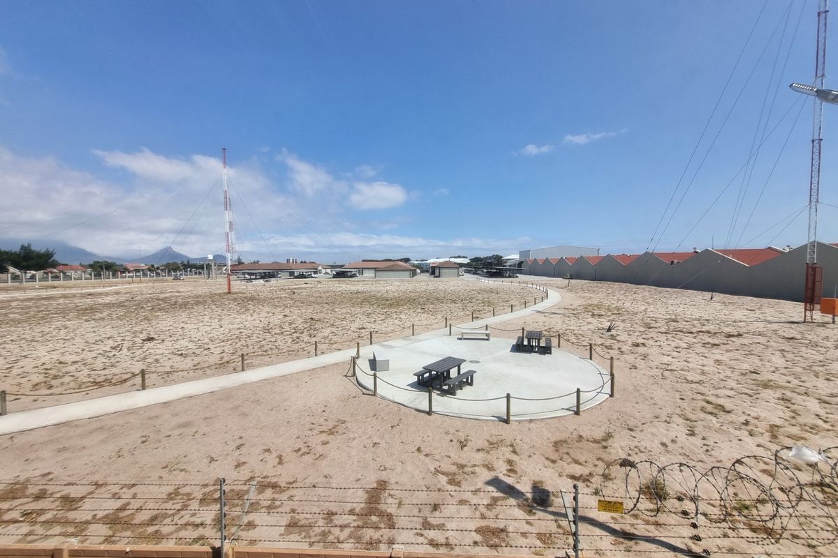 An expansive outdoor area featuring a concrete pathway, a circular patio space, and perimeter security fencing with barbed wire.