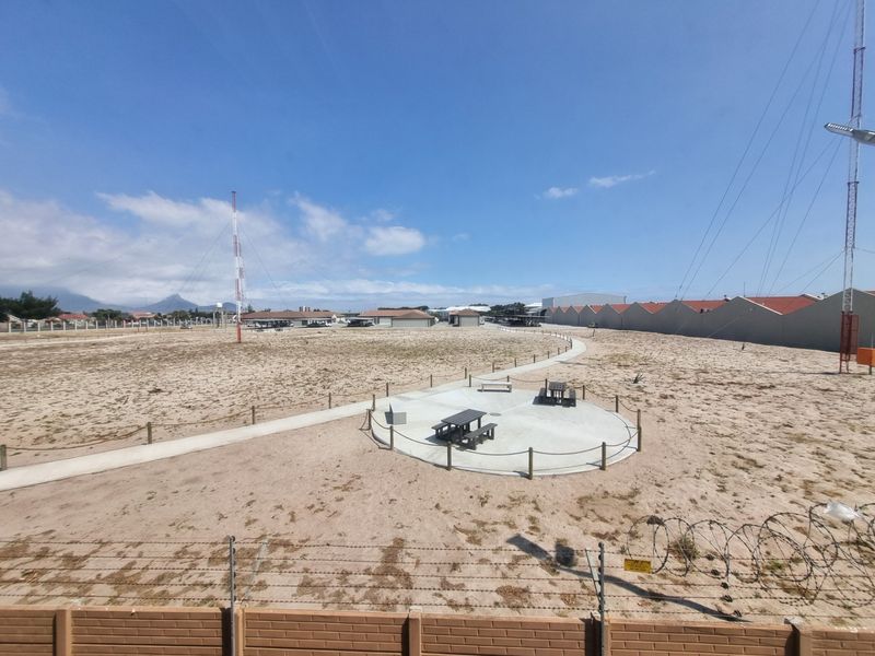 An expansive outdoor area featuring a concrete pathway, a circular patio space, and perimeter security fencing with barbed wire.