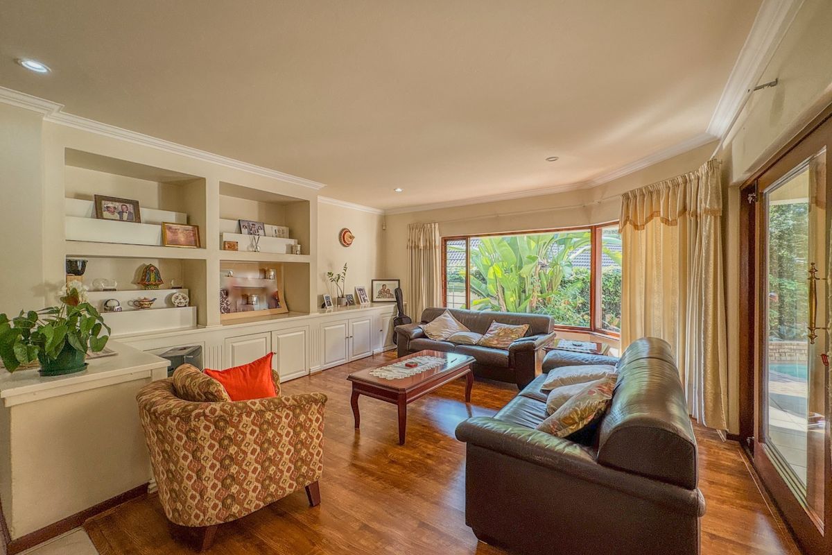 Spacious living room featuring hardwood flooring, built-in cabinetry, and a large bay window providing natural light and garden views.