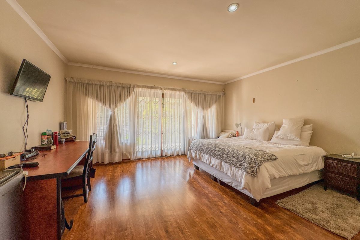 Spacious bedroom featuring warm laminate flooring, recessed lighting, and large sliding glass doors that provide access to the outdoor area.