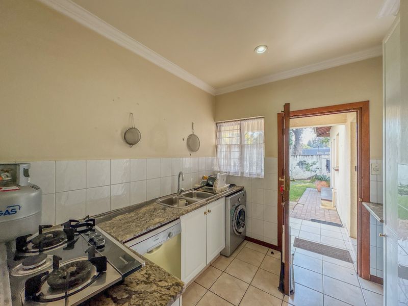 Functional kitchen featuring granite countertops, gas hob, and direct access to the rear exterior area.