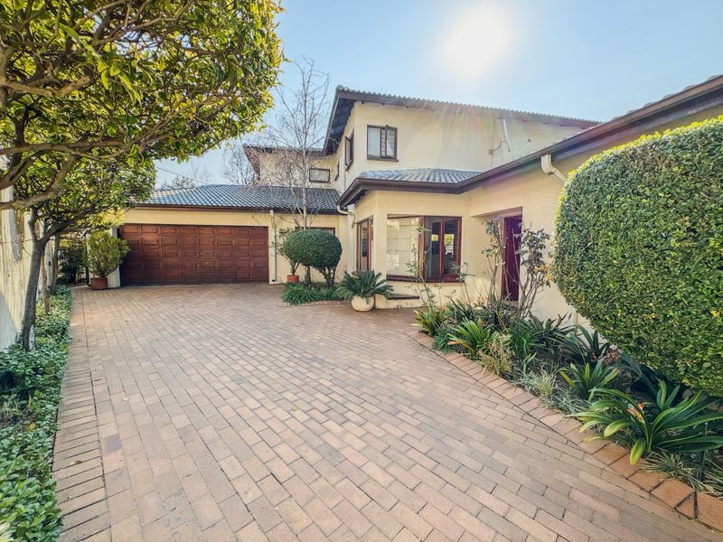 Front elevation of the apartment featuring a paved driveway, double garage, and well-maintained landscaped garden area.