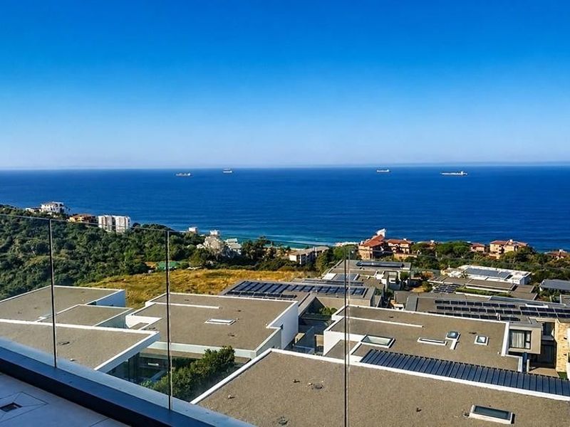 Expansive elevated ocean view from a modern balcony featuring a sleek glass balustrade and tiled flooring.