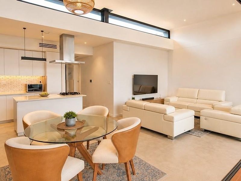 Modern open-plan living area featuring a sleek kitchen with integrated appliances, tiled floors, and large sliding doors opening to an outdoor space.