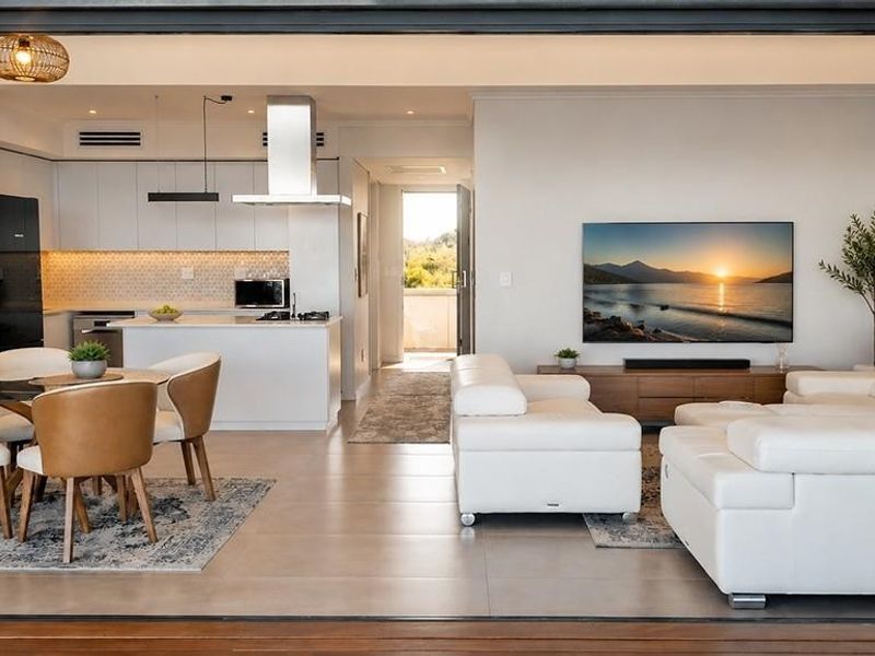 Modern open-plan living area featuring a sleek kitchen with integrated appliances, tiled floors, and seamless flow to the outdoor space.