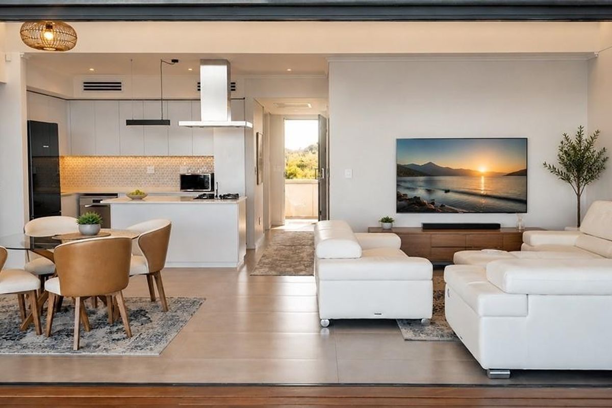 Modern open-plan living area featuring a sleek kitchen with integrated appliances, tiled floors, and seamless flow to the outdoor space.