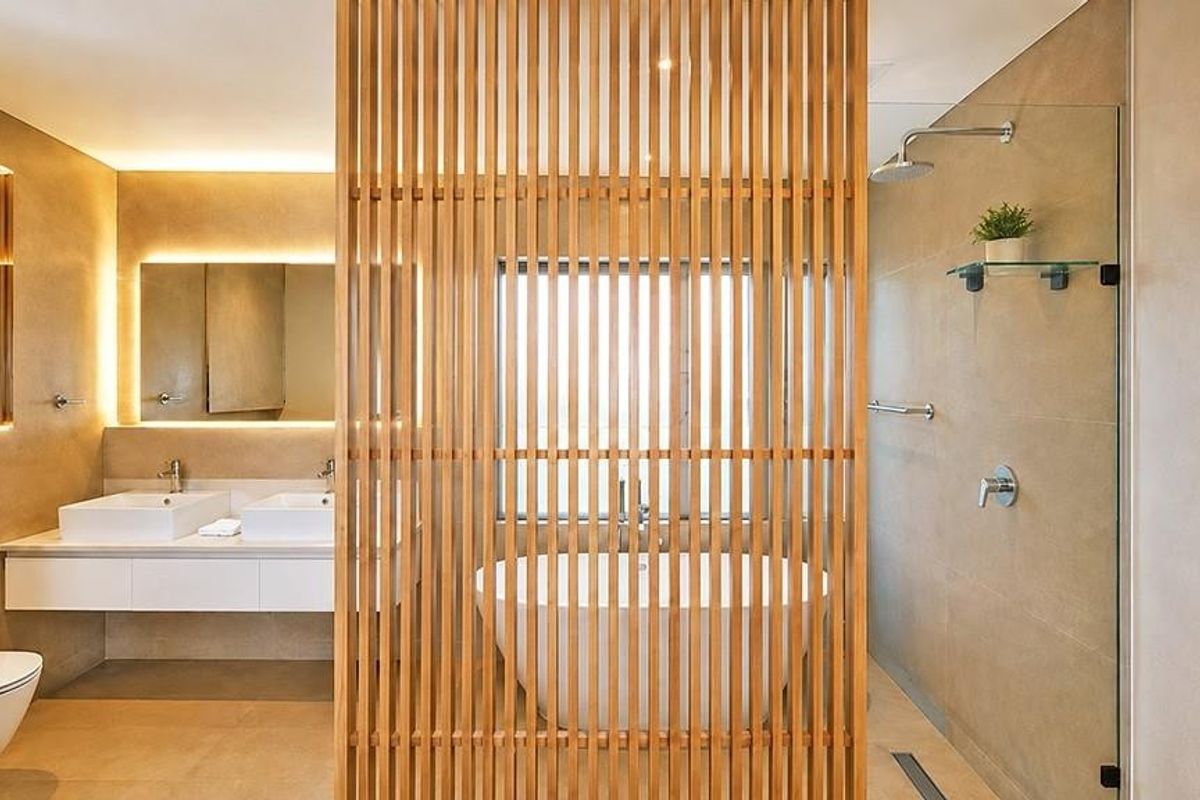 Modern luxury bathroom featuring a double vanity, freestanding bathtub, walk-in shower, and a stylish timber slat privacy screen.
