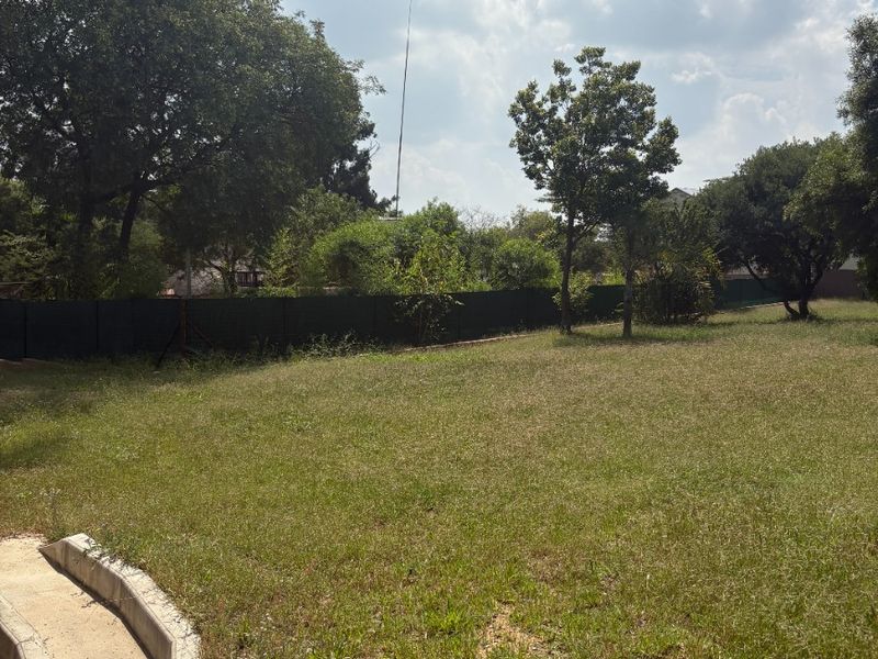 A spacious, open garden area featuring a lawn, concrete edging, and perimeter fencing, offering potential for landscaping and outdoor development.