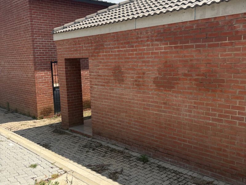 Exterior view of a brick farm building featuring a tiled roof and paved walkway area.
