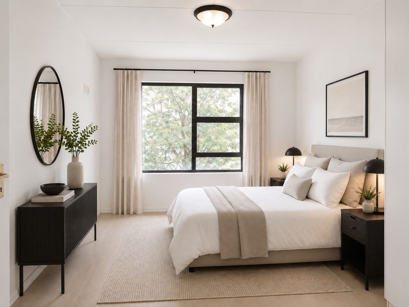 A bright and well-maintained bedroom featuring a large black-framed window, neutral finishes, and a built-in wardrobe.