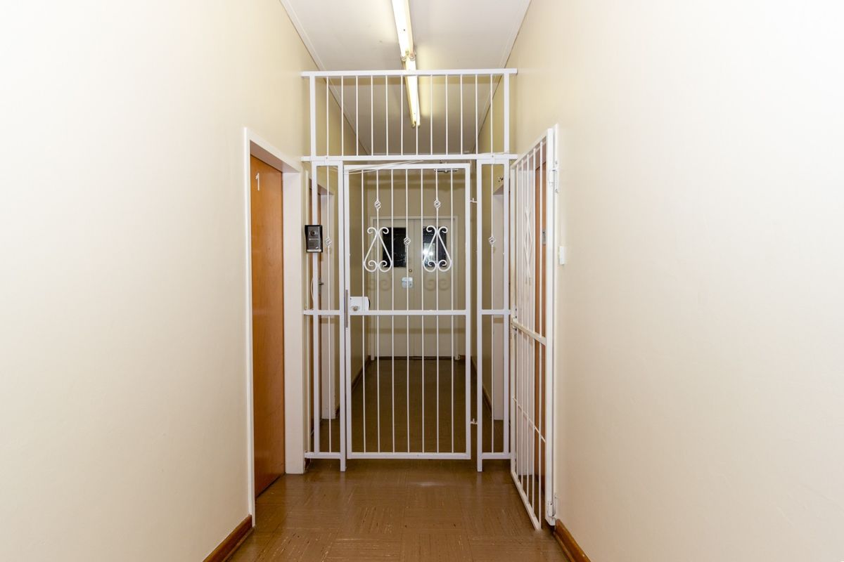 A functional office hallway featuring vinyl flooring, a security gate, and an intercom system, providing access to individual office units.
