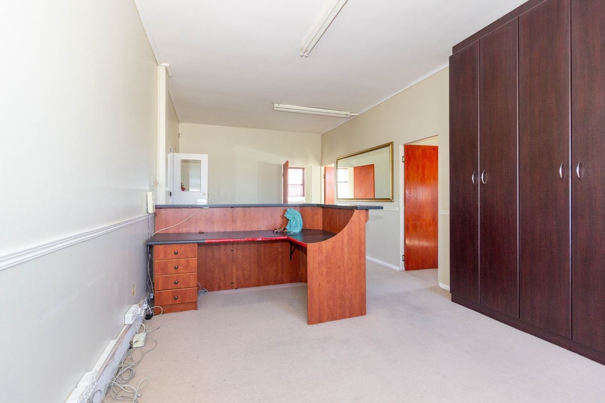 Office space featuring a built-in reception desk, large storage cabinetry, carpeted flooring, and functional fluorescent lighting.