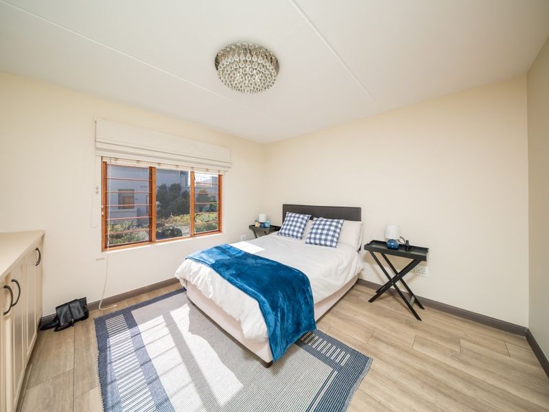 A well-lit bedroom featuring laminate flooring, built-in cabinetry, and a window with security bars.
