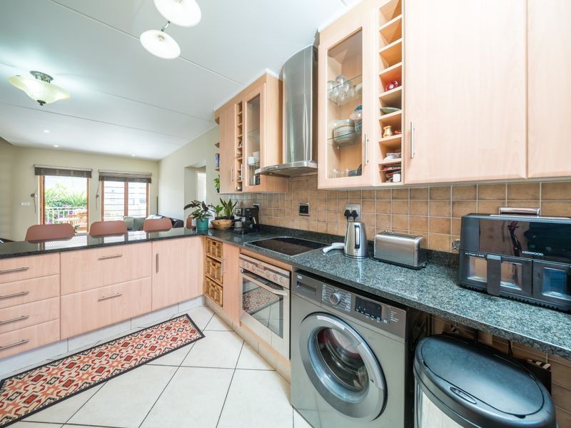 A functional kitchen featuring light wood cabinetry, granite countertops, integrated appliances, and a breakfast bar, seamlessly flowing into the adjacent living area.