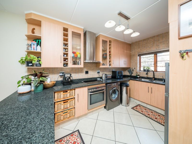 A functional kitchen featuring light wood cabinetry, granite countertops, a built-in oven with hob, and a tiled backsplash.