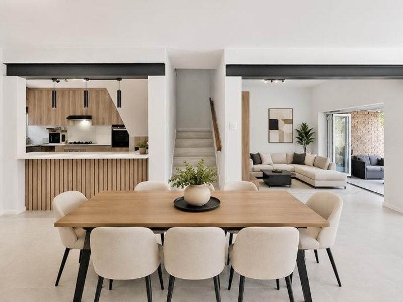 Modern open-plan living area featuring a contemporary kitchen, dining space, and seamless flow to an outdoor patio through bi-fold doors.