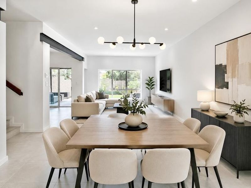 Spacious open-plan living and dining area featuring modern finishes, tiled flooring, a contemporary chandelier, and seamless access to the outdoor patio.