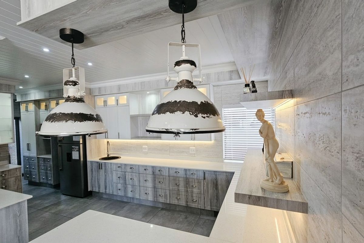 Modern kitchen featuring high-end cabinetry, stone countertops, integrated lighting, and a stylish tiled backsplash, offering a contemporary and functional culinary space.