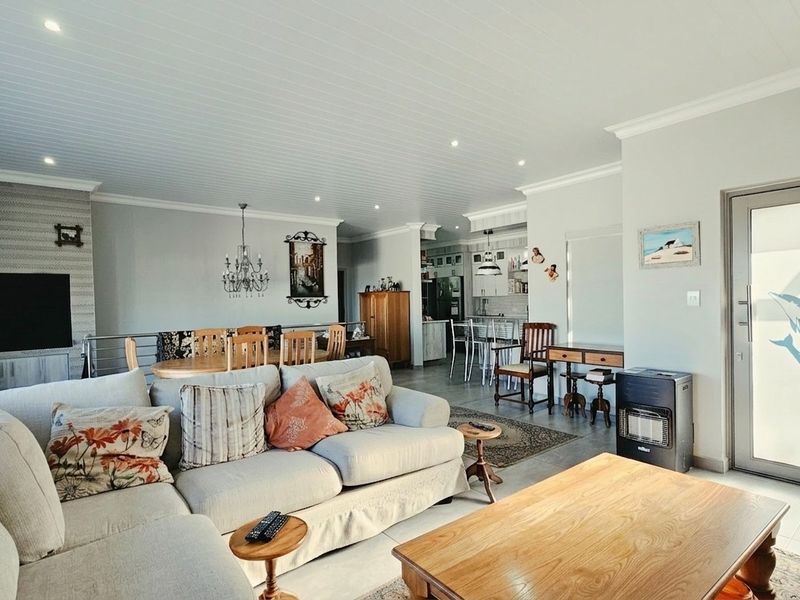 Spacious open-plan living area featuring a modern kitchen, dining space, and lounge with tiled floors, recessed lighting, and direct access to the outdoors.