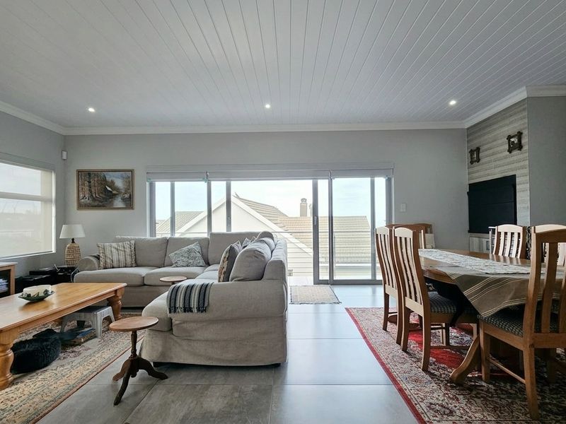 Spacious open-plan living and dining area featuring tiled floors, a tongue and groove ceiling, and sliding glass doors leading to an outdoor space.