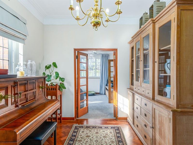 A well-maintained living area featuring classic parquet flooring, elegant crown molding, and custom built-in cabinetry, with French doors leading to an adjacent room.