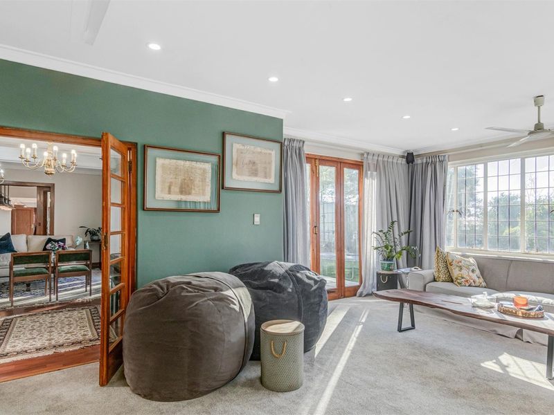 Spacious living room featuring recessed lighting, a ceiling fan, and classic french doors opening to the exterior, with views through leaded glass windows.