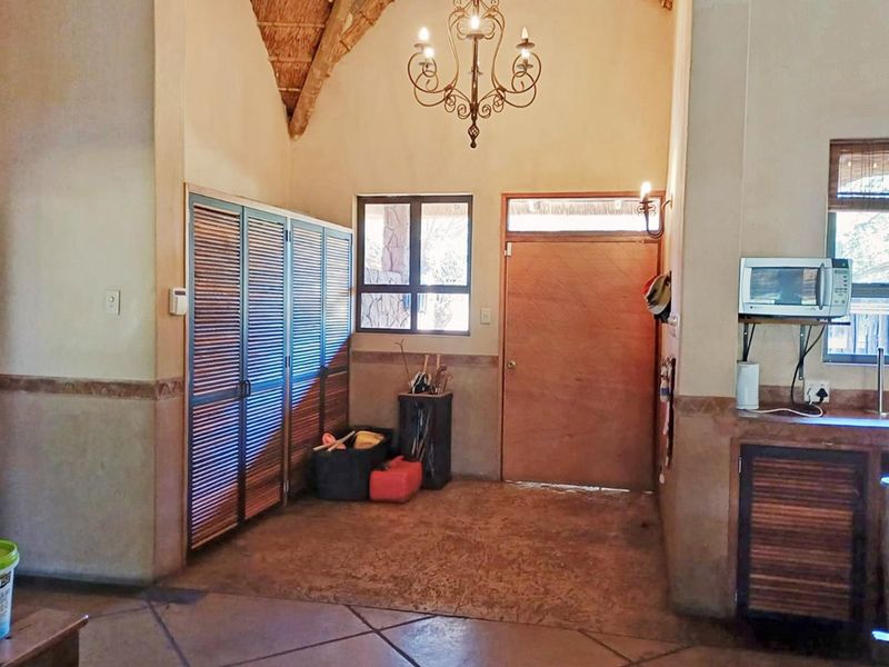 Entrance area featuring a high vaulted thatched ceiling, tiled flooring, and built-in louvered storage cupboards.