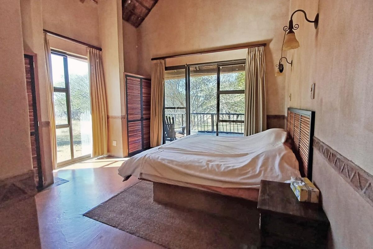 Spacious bedroom featuring a vaulted ceiling with exposed thatch, built-in cabinetry, and large sliding glass doors opening to an outdoor deck area.