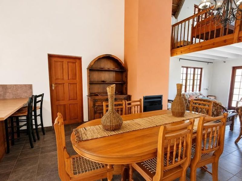 Open-plan living and dining area featuring a built-in fireplace, tiled flooring, and a mezzanine level with a wooden balustrade.