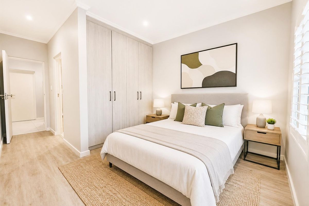 A well-maintained bedroom featuring light-toned laminate flooring, built-in cupboards, and modern recessed lighting, creating a bright and inviting living space.