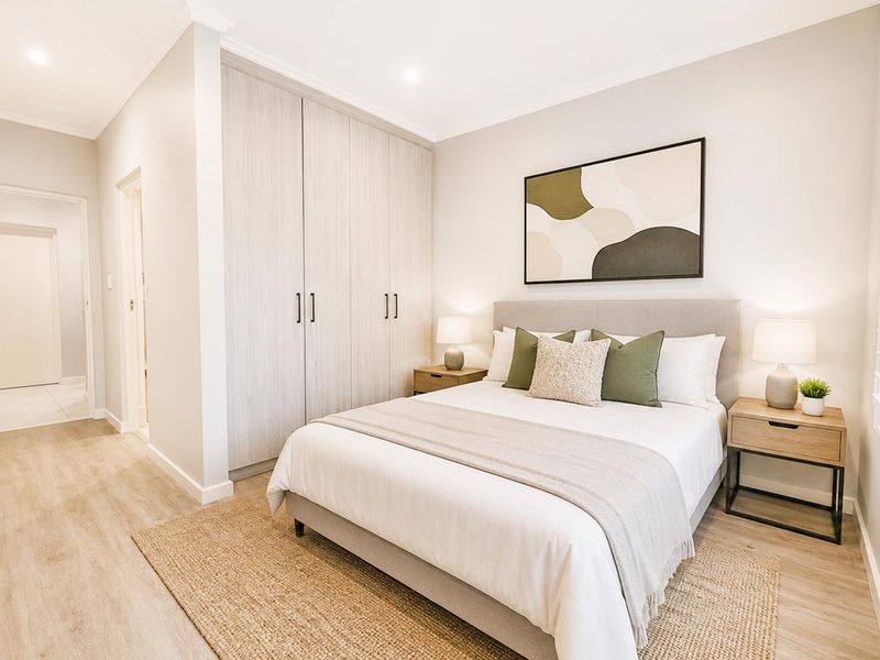 A well-maintained bedroom featuring light-toned laminate flooring, built-in cupboards, and modern recessed lighting, creating a bright and inviting living space.