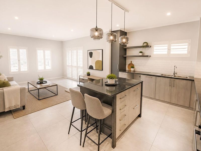 Modern open-plan living area featuring a contemporary kitchen with a central island, stone countertops, subway tile backsplash, and elegant pendant lighting.