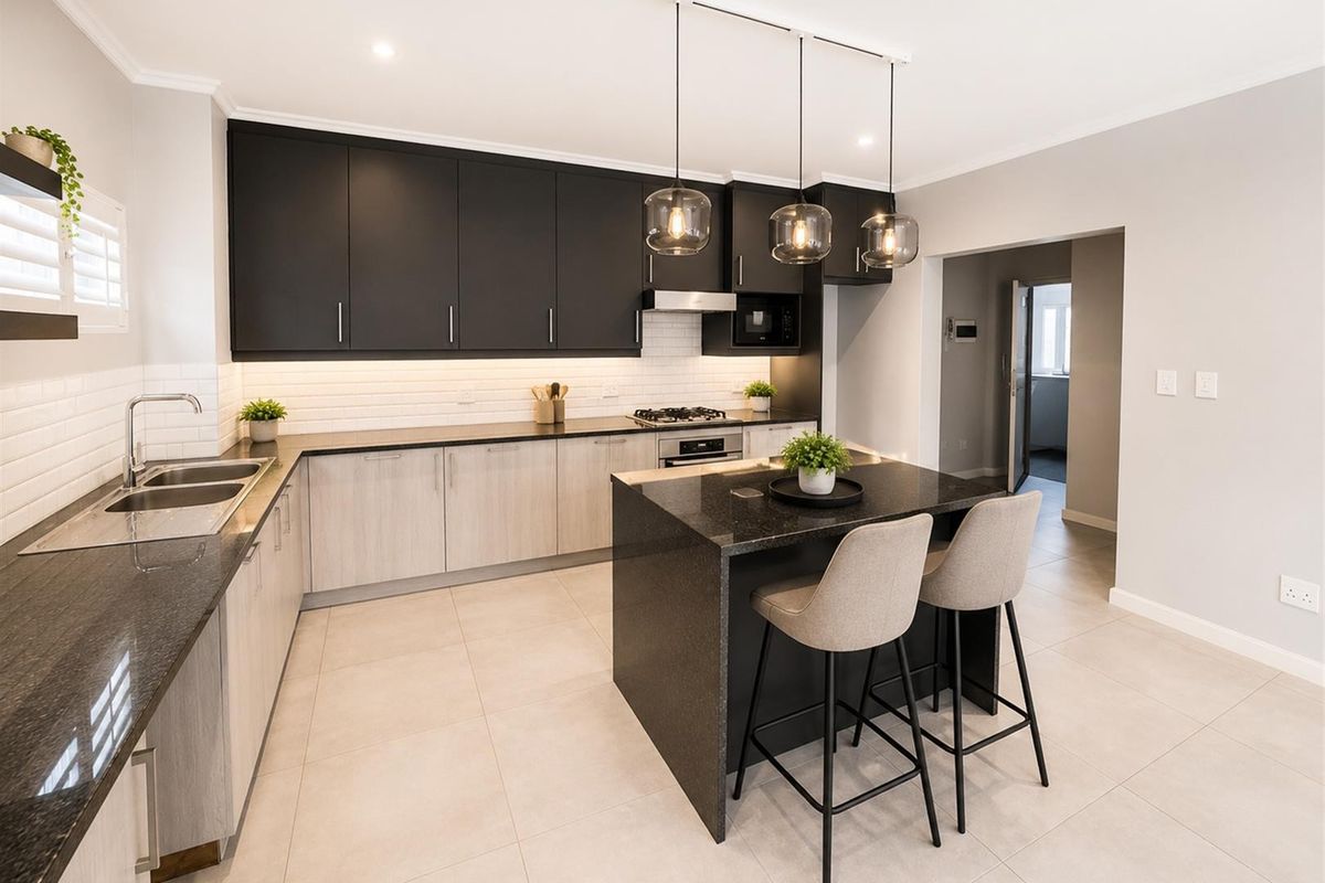 Modern kitchen featuring two-tone cabinetry, stone countertops, a central island with breakfast bar seating, and integrated appliances.