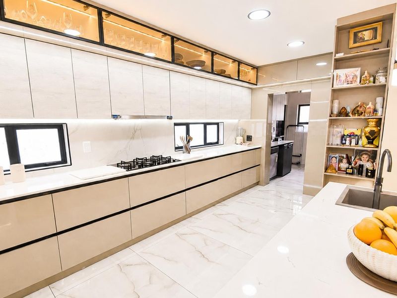 Modern, high-end kitchen featuring sleek handleless cabinetry, stone countertops, integrated gas hob, and elegant marble-look flooring with ample storage and recessed lighting.