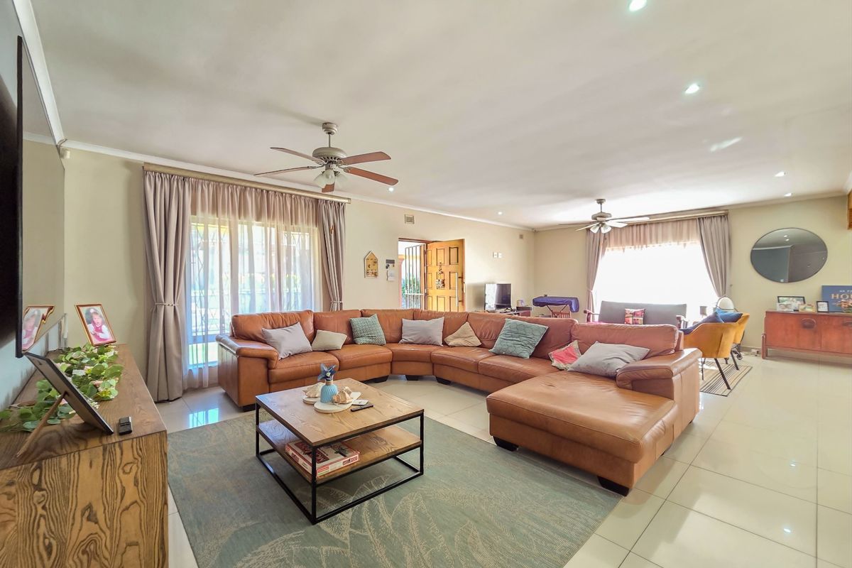 Spacious open-plan living area featuring neutral tiled flooring, recessed lighting, and dual ceiling fans, with large sliding doors providing natural light.