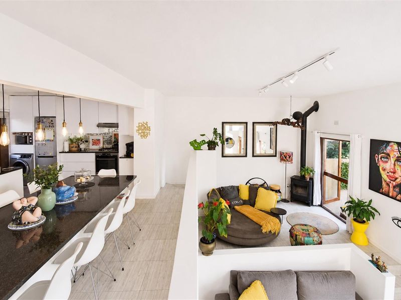 Open-plan living area featuring a modern kitchen with granite island, wood-burning fireplace, and direct access to the outdoor space through glass sliding doors.