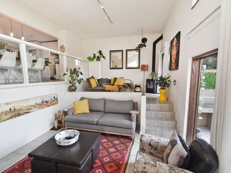 A split-level open-plan living area featuring tiled floors, a wood-burning fireplace, and a glass balustrade overlooking the kitchen space.
