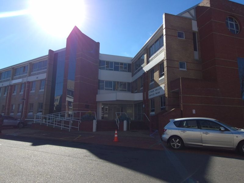 Front elevation of a multi-story brick office park building featuring glass facade elements, a wheelchair ramp, and access to underground parking.