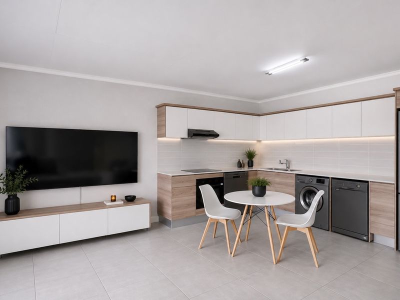 Modern open-plan living area featuring a sleek kitchen with built-in cabinetry, integrated appliances, and neutral tiled flooring throughout.