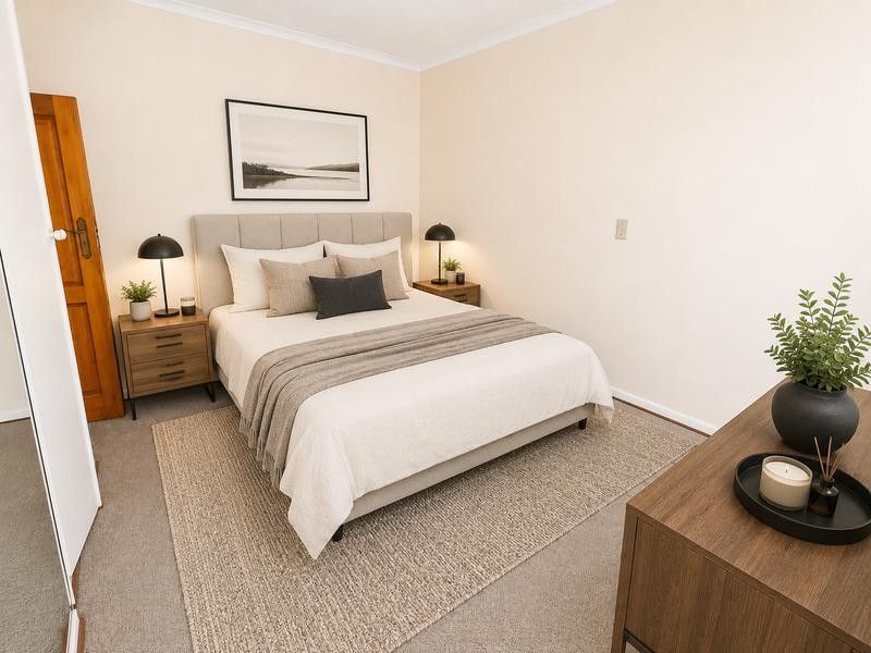 A well-maintained bedroom featuring neutral wall tones, carpeted flooring, and coved ceiling detailing, providing a comfortable and inviting living space.