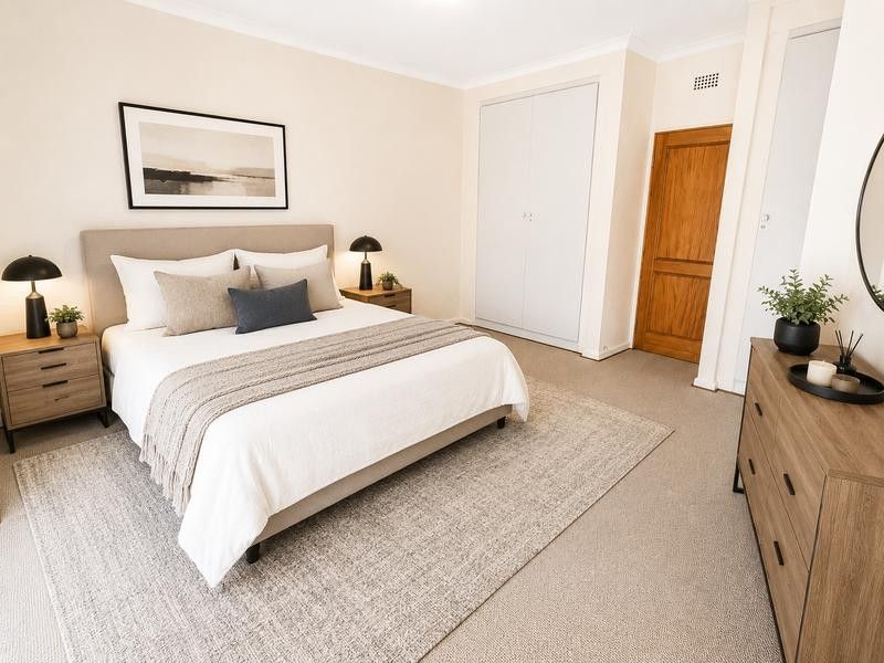 A well-maintained bedroom featuring neutral walls, carpeted flooring, and a built-in wardrobe with a classic timber door.
