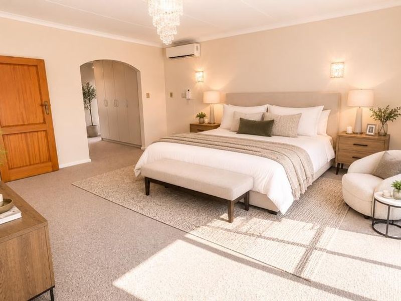 Spacious bedroom featuring neutral carpeting, built-in cupboards, air conditioning, and elegant lighting fixtures, creating a comfortable and well-maintained living space.