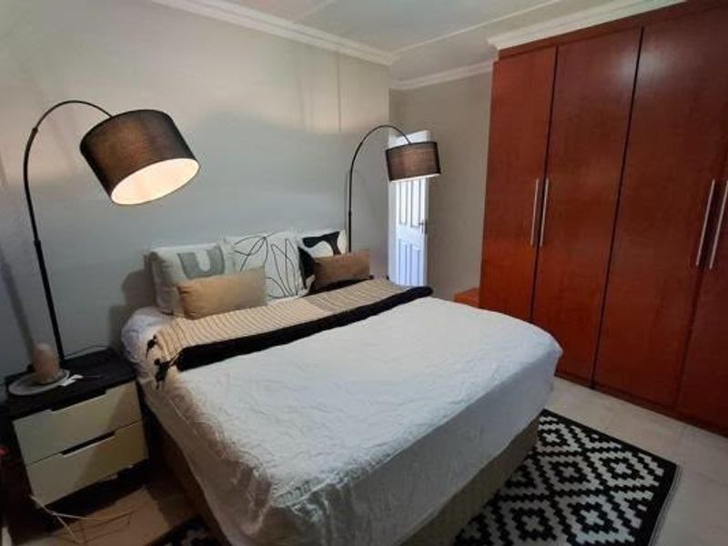 A well-maintained bedroom featuring ample built-in wooden cupboards and classic crown molding, providing a functional and comfortable living space.